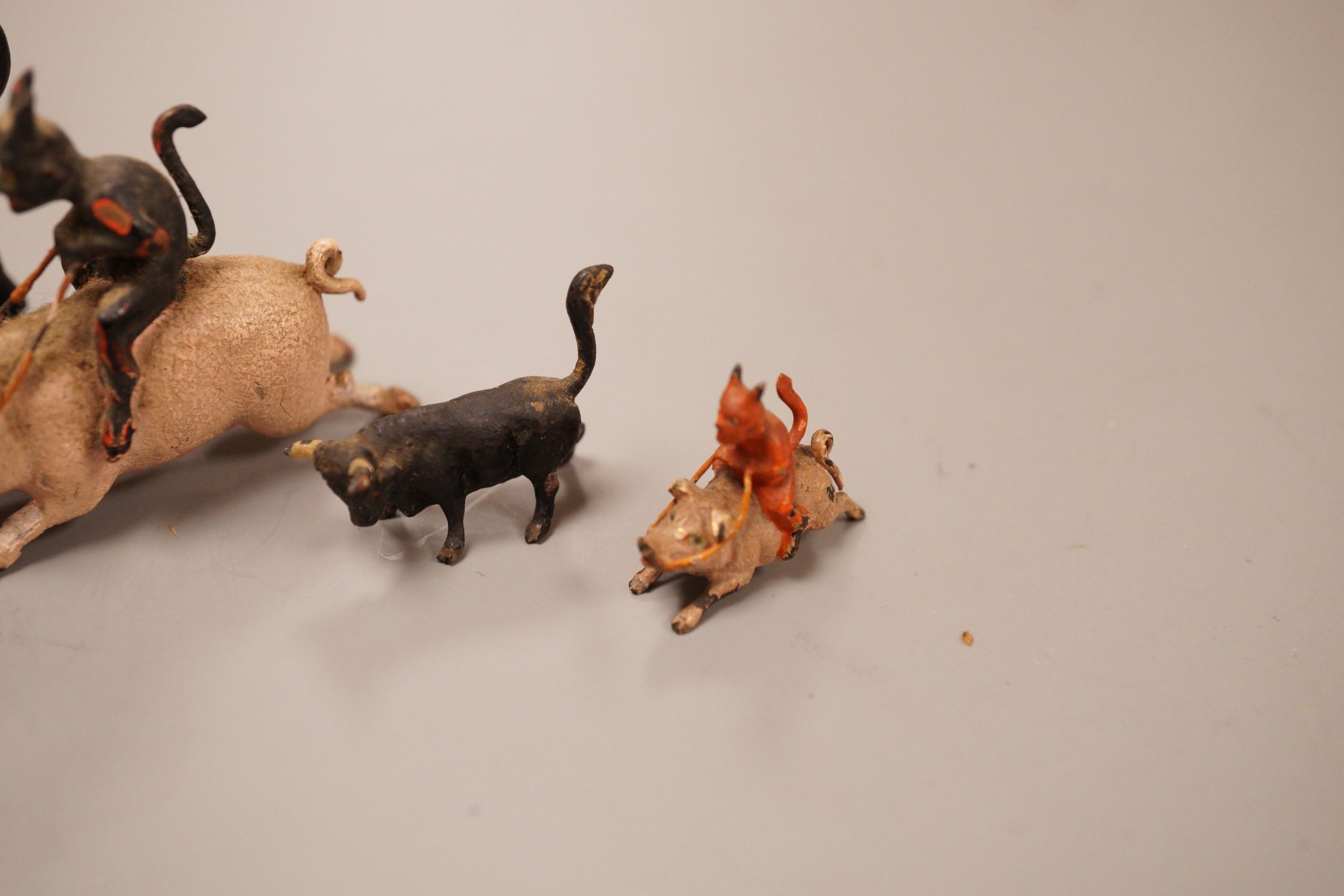 Four Austrian cold painted bronze miniature groups or figures, two of the devil riding a pig and two of cattle, tallest 4cm